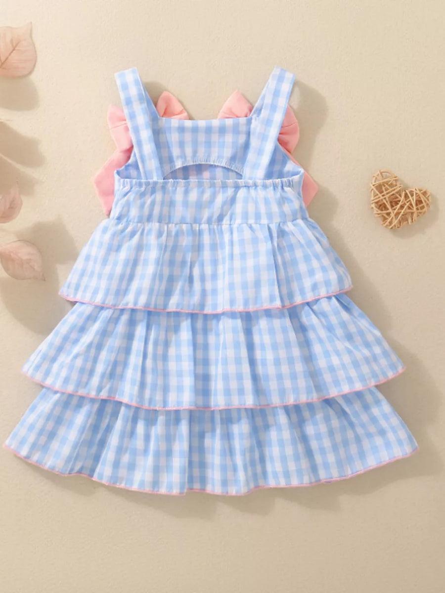Blue gingham baby dress with tiered ruffles and pink bow accents on back.
