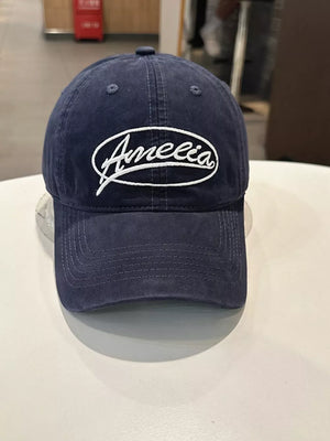 Navy baseball cap with white Amelia embroidery and curved brim.