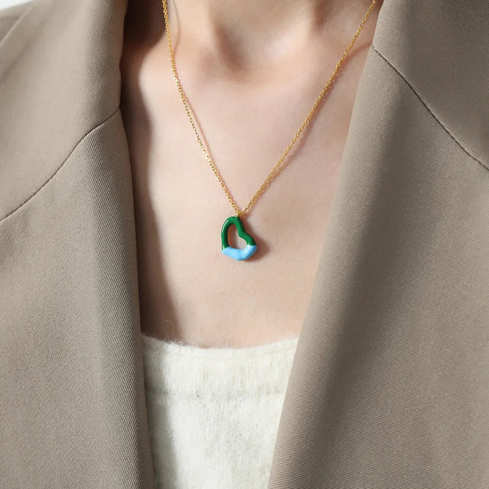 Gold necklace with a two-tone green and blue heart pendant.