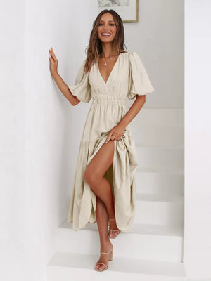 Beige midi dress with puff sleeves, V-neck, cinched waist, and tiered skirt with high slit.