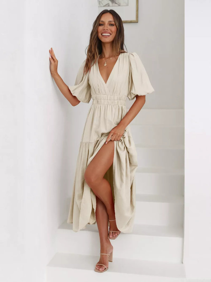Beige midi dress with puff sleeves, V-neck, cinched waist, and tiered skirt with high slit.