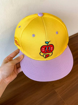 Yellow baseball cap with purple brim and embroidered apple graphic.
