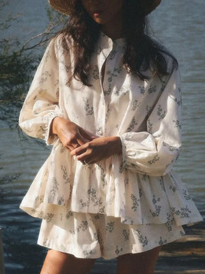 Cream floral print tiered mini dress with long sleeves and a high neckline.