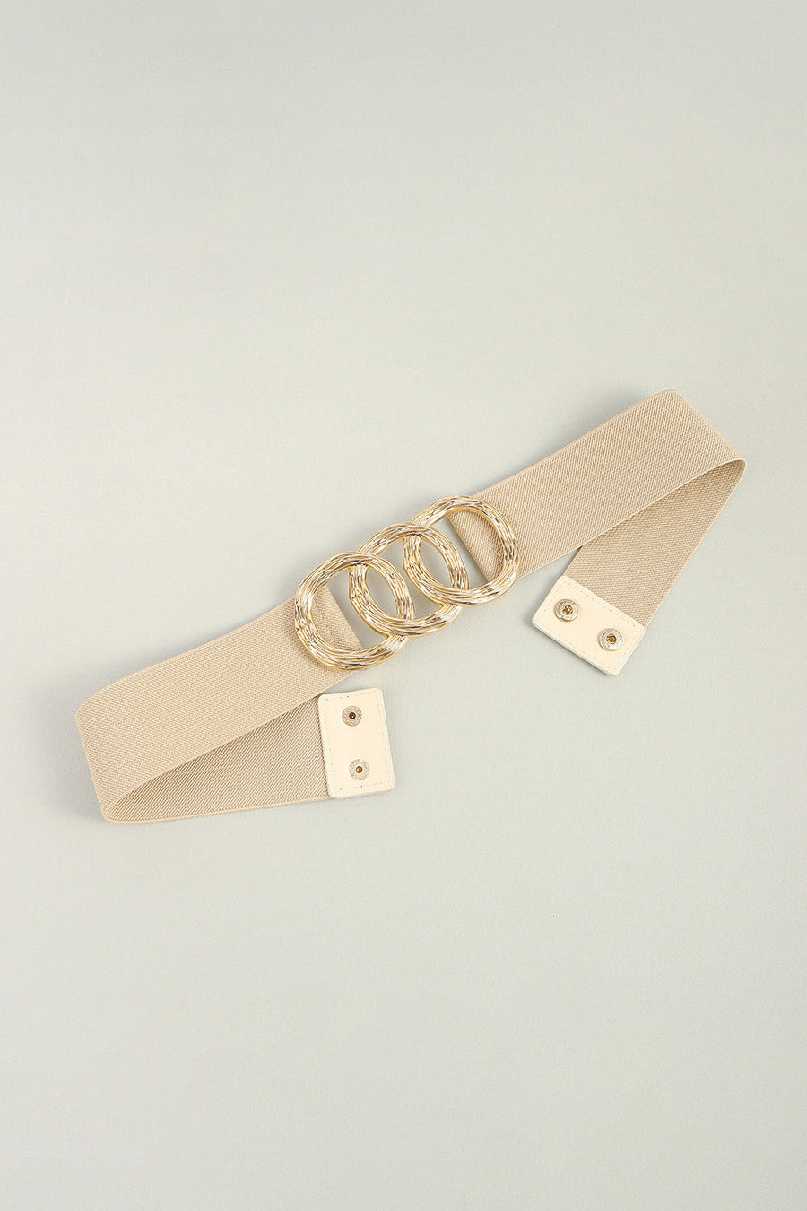 Tan elastic belt with triple gold ring buckle detail and faux leather snap closure.