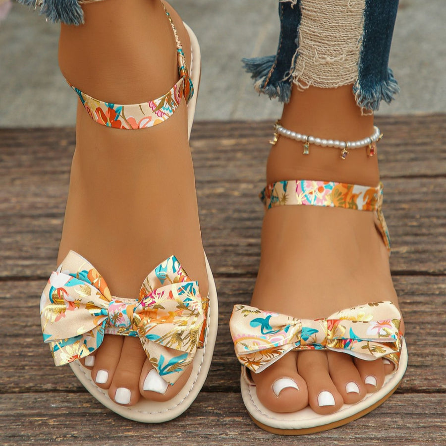 Beige flat sandals with floral print bowknot detail and ankle strap.