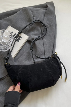 Black suede crescent shoulder bag with knot strap detail and gold hardware