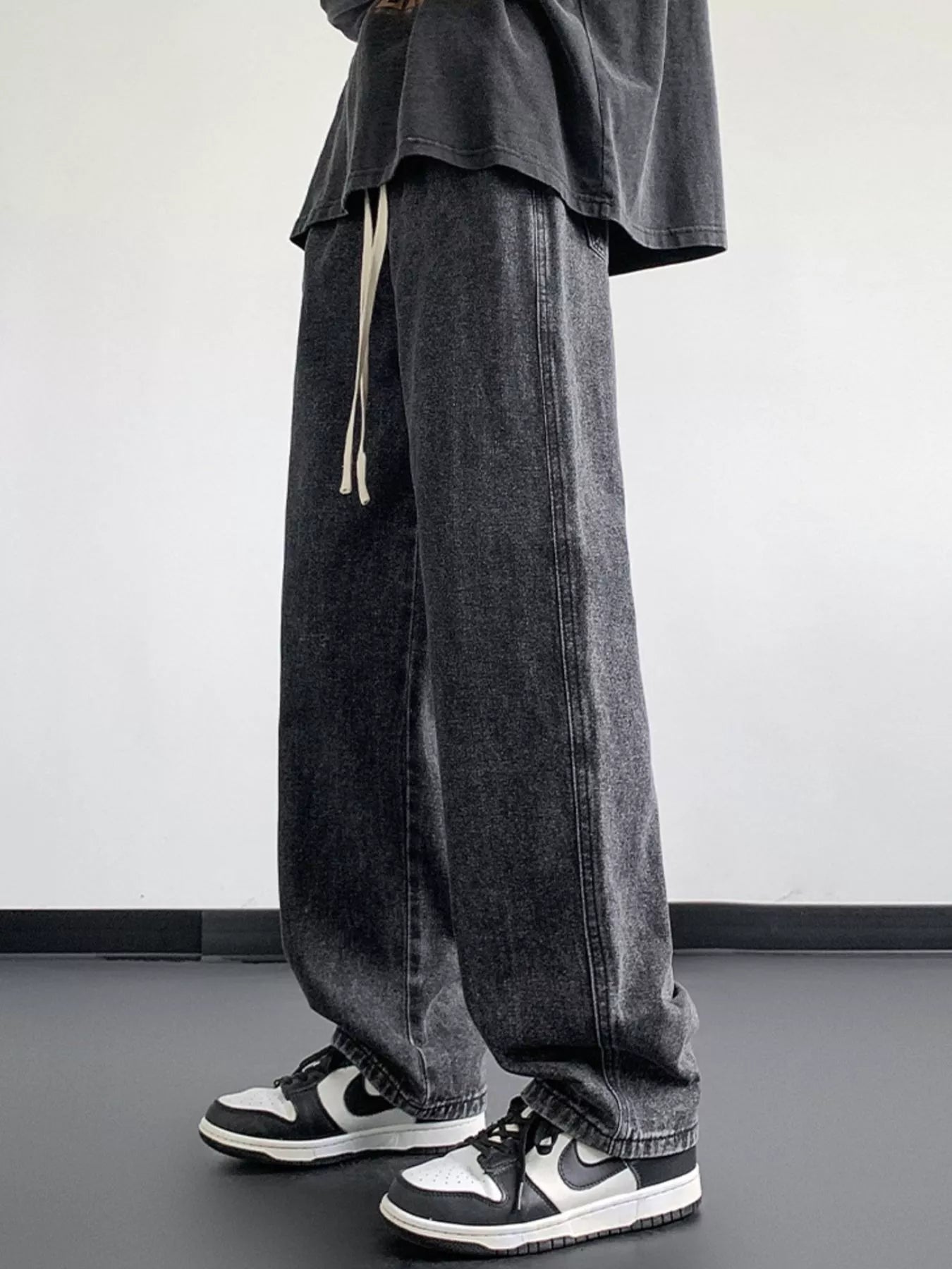 Oversized drawstring jeans in dark gray wash with a loose fit and casual styling.