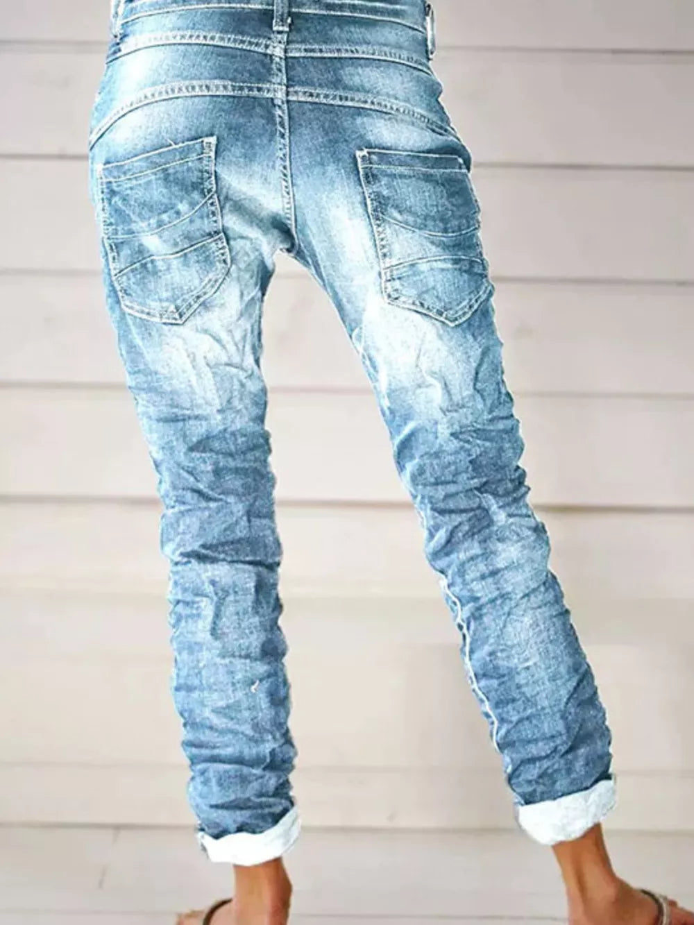 Light blue cuffed button-fly jeans with distressed detailing and ruched legs.