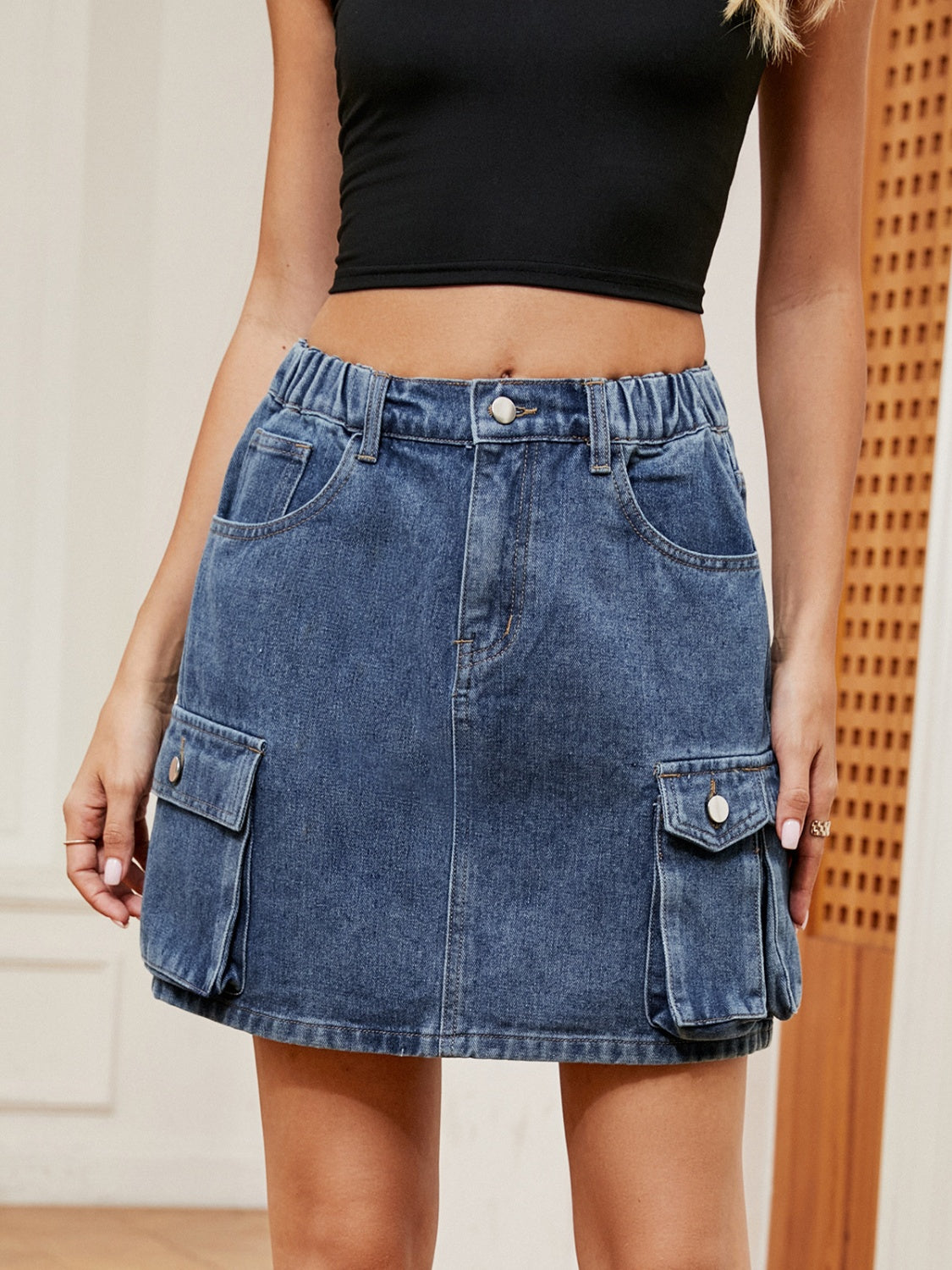 Denim cargo mini skirt in dark blue with elastic waistband and button closure.