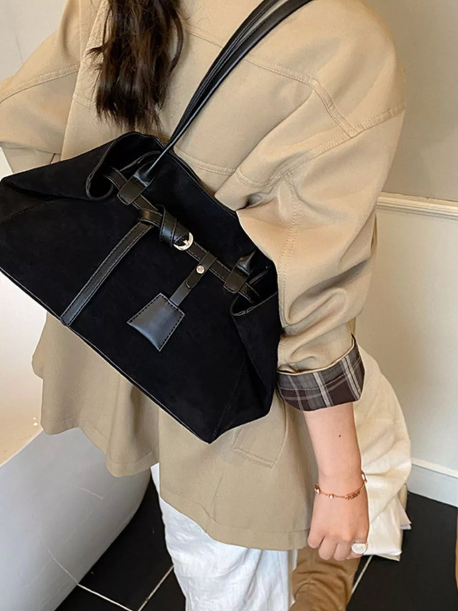 Black suede shoulder bag with leather trim and buckle detail.