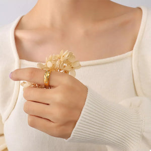 Gold ring with zircon accents on a woman's finger, styled with a cream sweater.