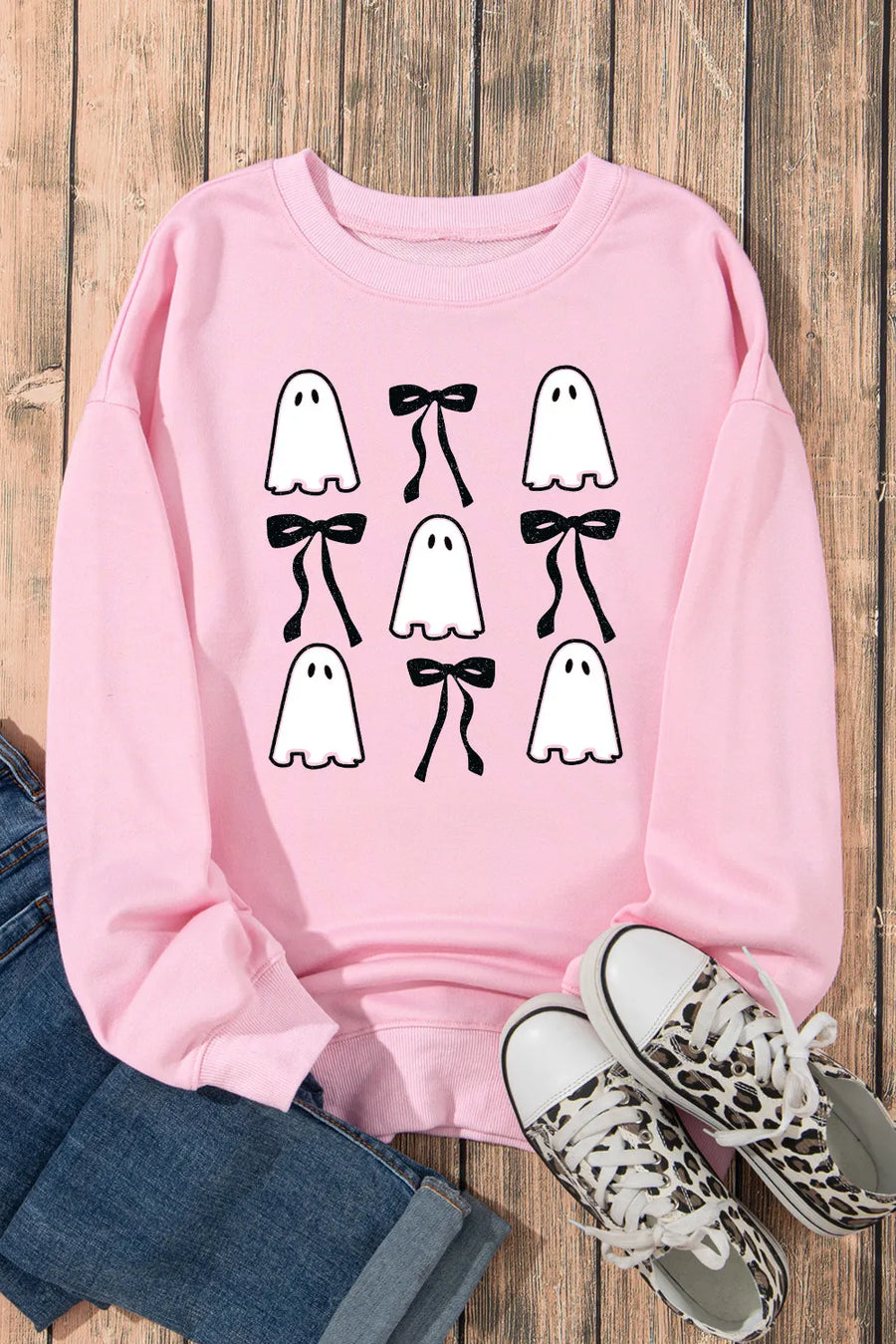 Blush pink sweatshirt with a ghost and bow graphic pattern.