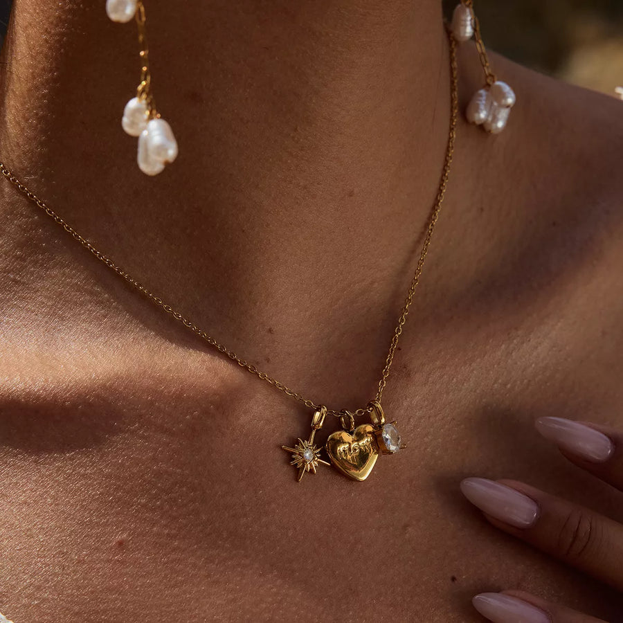 Gold heart charm necklace with starburst and crystal accents, perfect for mom.