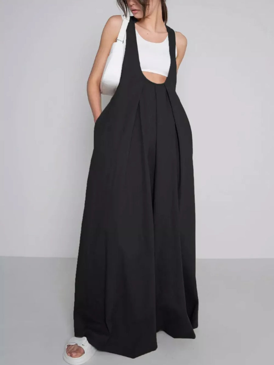 Black pleated overall dress with pockets and wide legs.