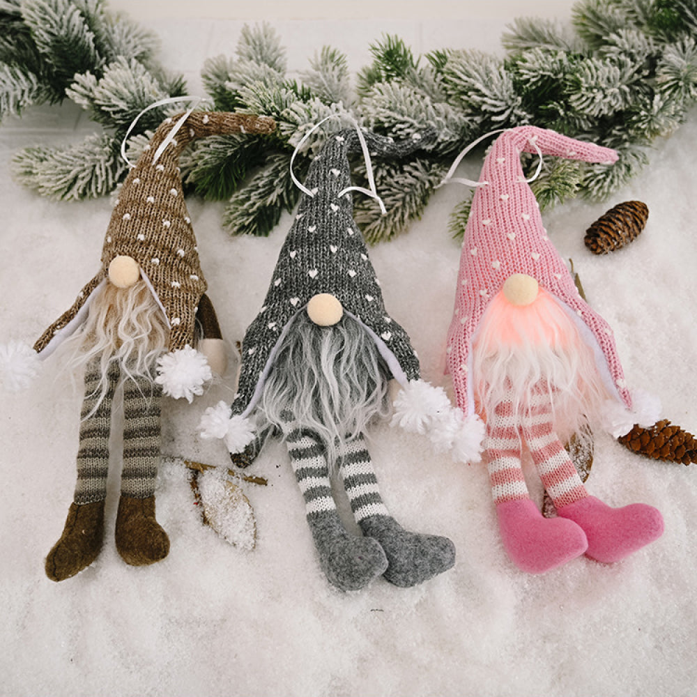 Knitted gnome ornaments in light gray, blush pink, and khaki with striped legs and pom-pom accents.