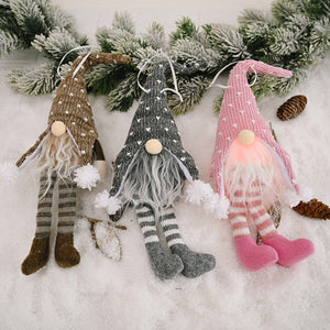 Knitted gnome ornaments in light gray, blush pink, and khaki with striped legs and pom-pom accents.
