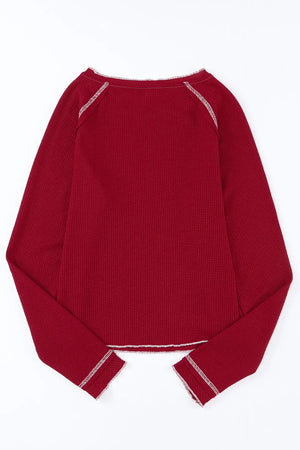 Burgundy waffle knit crewneck top with contrast stitching on neckline and cuffs.