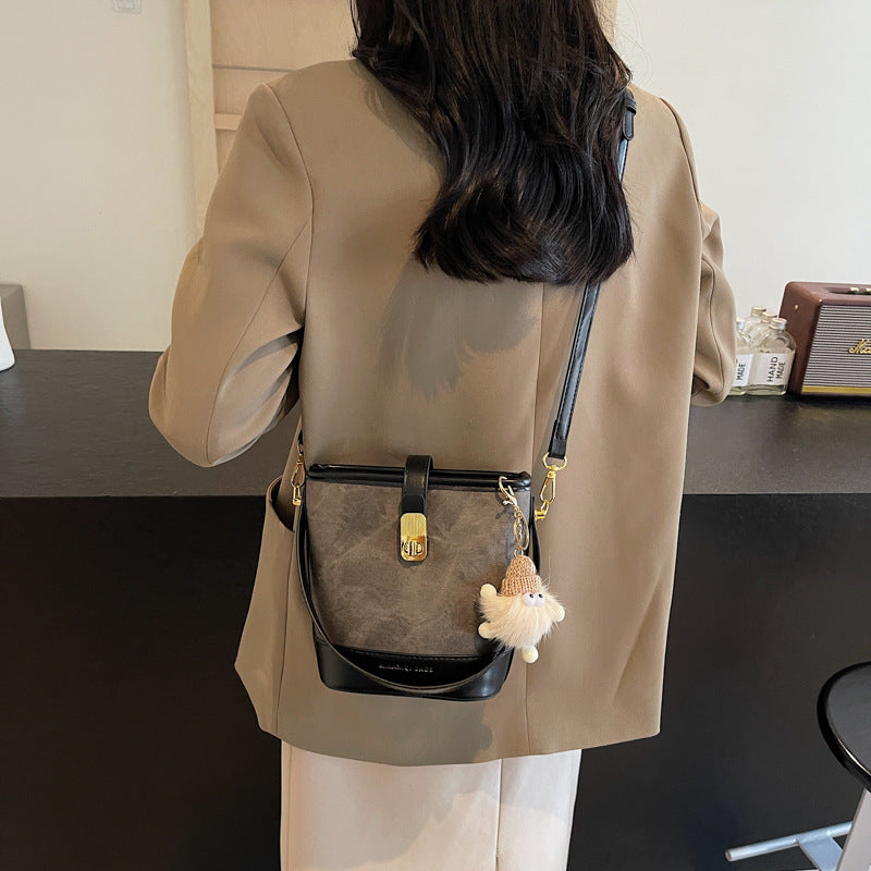 Vintage bucket crossbody bag in black with gold hardware and a fuzzy charm.