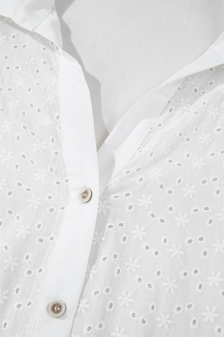 White eyelet blouse with embroidered floral details and button front.