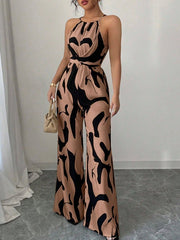 Elegant wide-leg jumpsuit in tan with black abstract print, halter neck, and draped bodice.