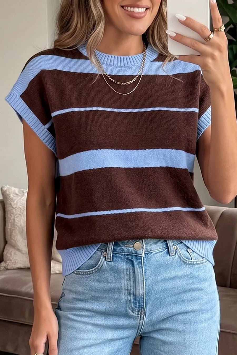 Chic striped knit sweater vest with crew neck and ribbed details, styled with jeans.
