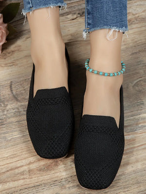 Black knit ballet flats with a textured pattern and a turquoise beaded anklet.