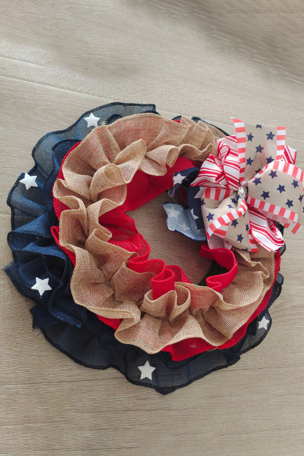 Patriotic ruffled burlap wreath with red, white, and blue stars and stripes bow.