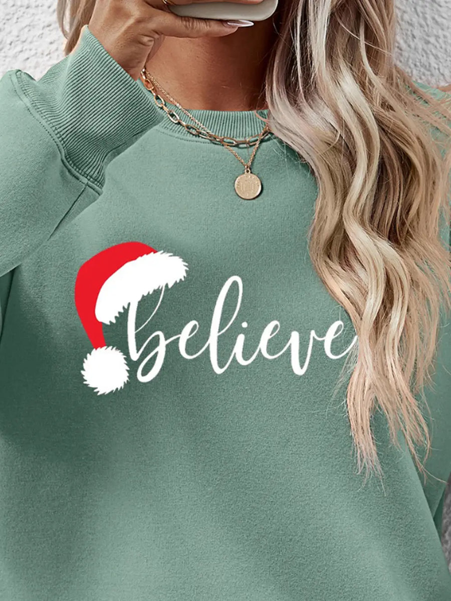 Sage raglan sweatshirt with white "believe" graphic and Santa hat detail.