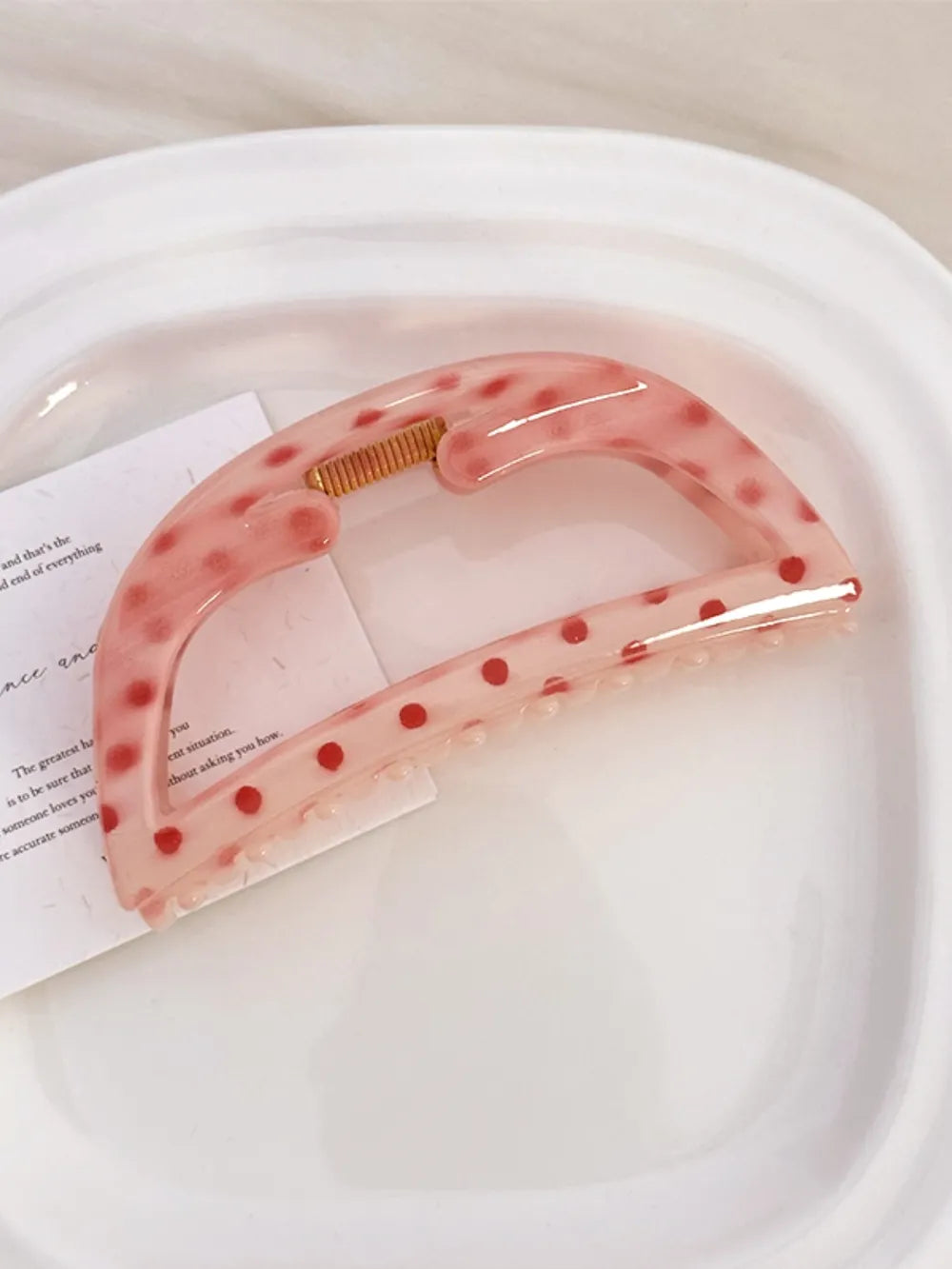 Polka dot claw hair clip in Style A, a translucent pink with red dots.