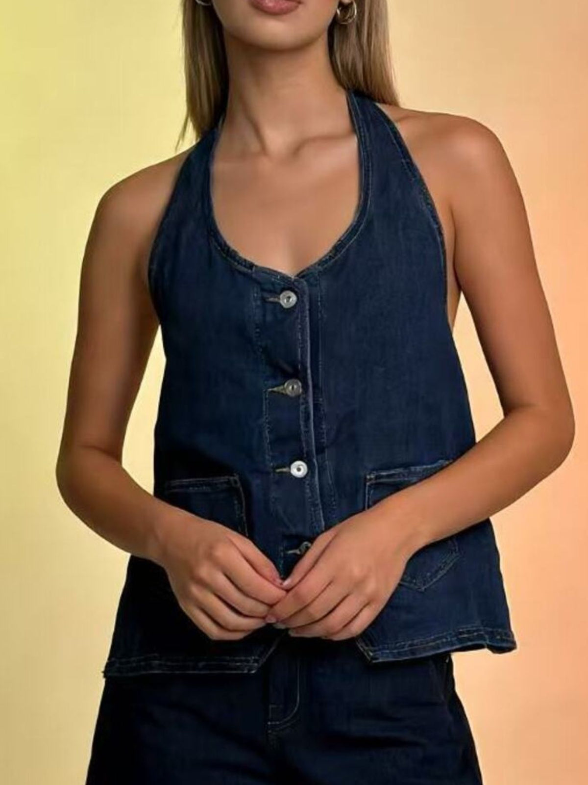 Dark blue denim halter vest with button-down front and pocket details.
