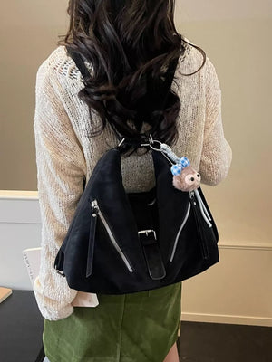 Black distressed leather buckle shoulder bag with diagonal zippers and a charm.