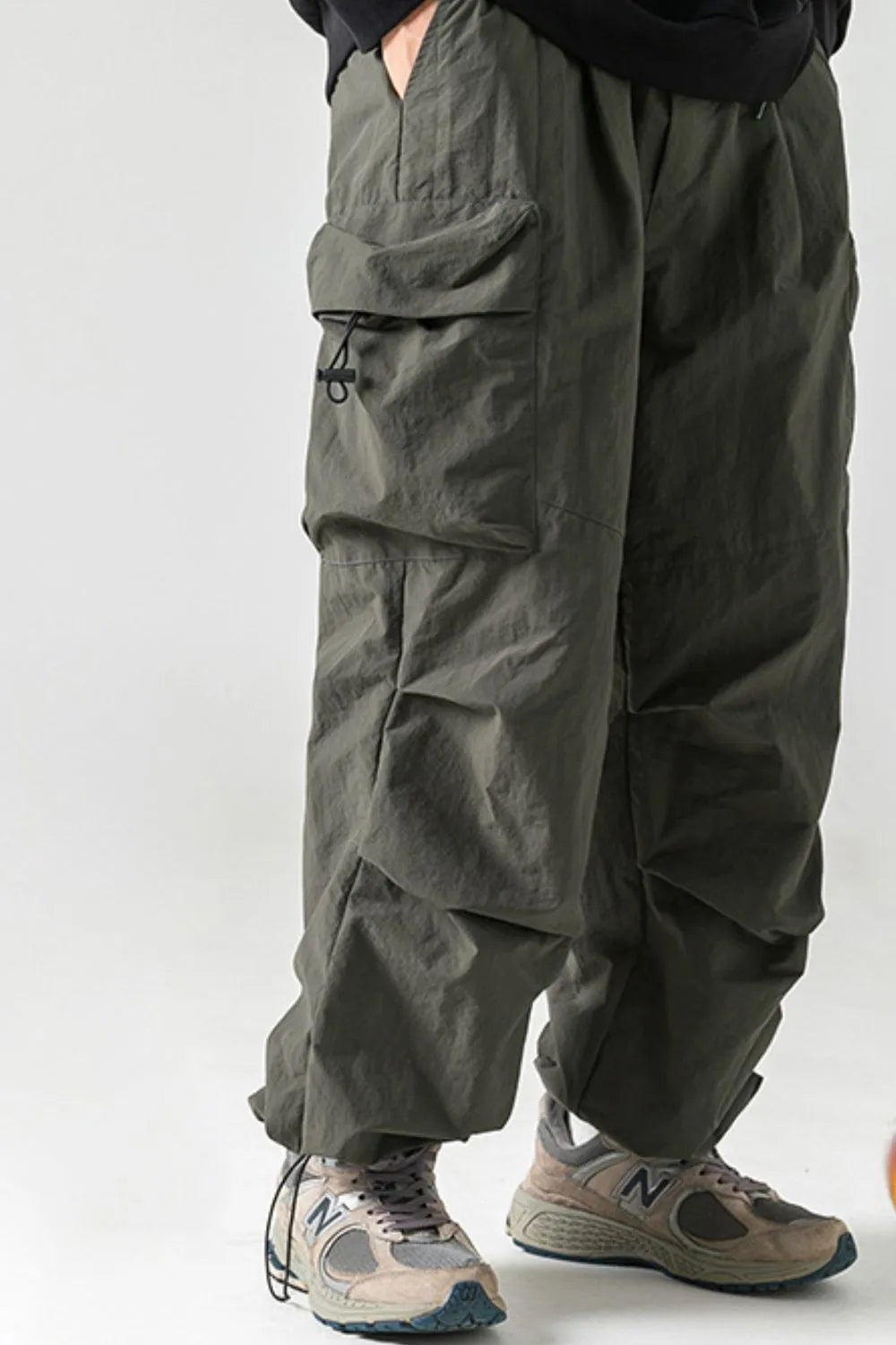Oversized utility cargo trousers in dark gray with multiple pockets and drawstring details.