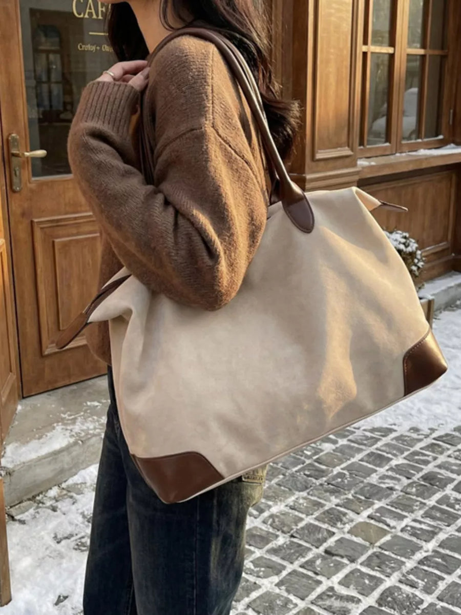 Chic beige slouchy travel bag with camel leather accents and top handles.