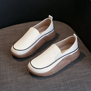 Ivory slip-on sneakers with sculpted platform soles and black trim detail.