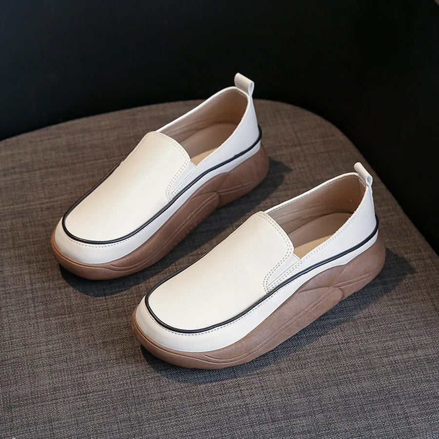 Ivory slip-on sneakers with sculpted platform soles and black trim detail.