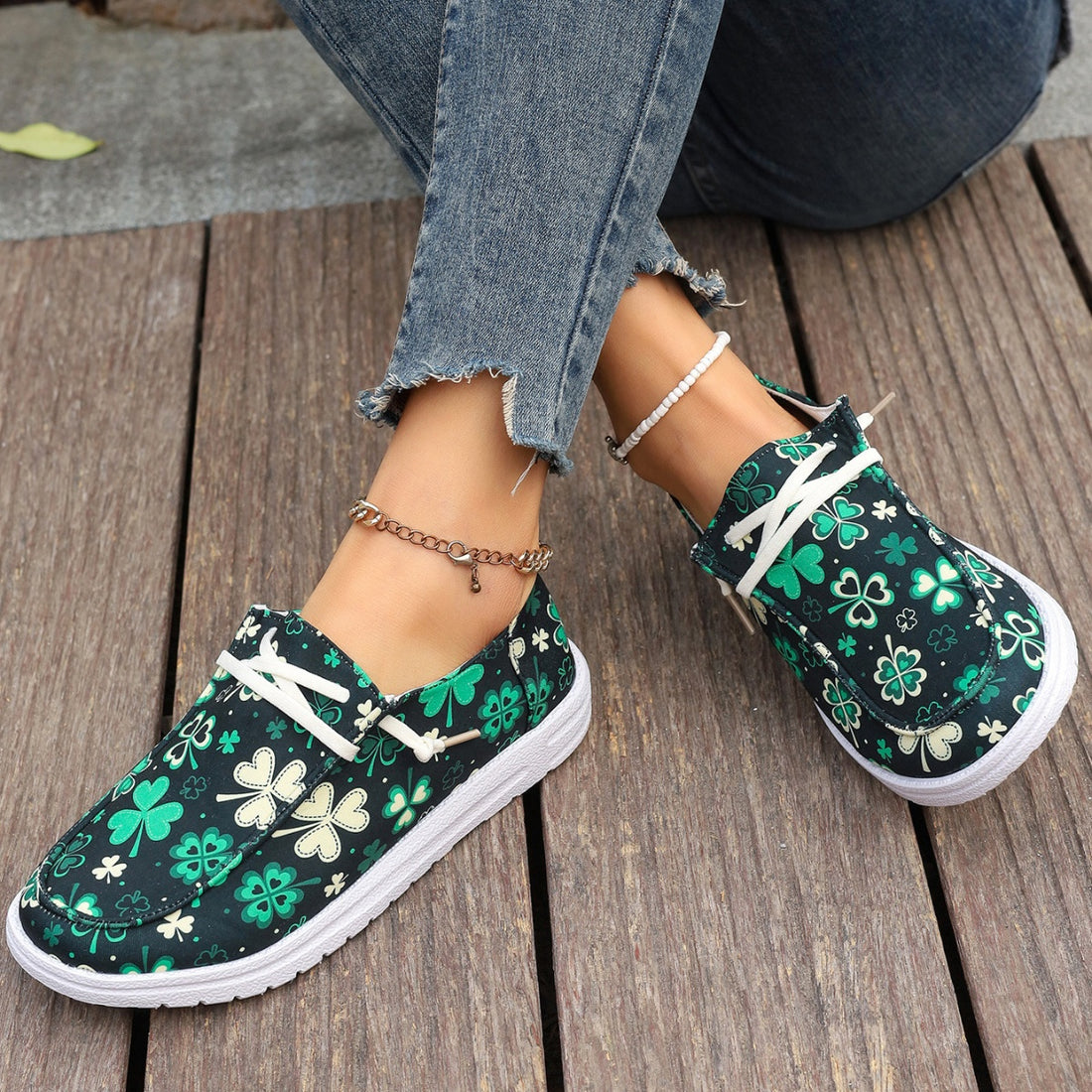 Clover print canvas slip-on sneakers with decorative white laces.