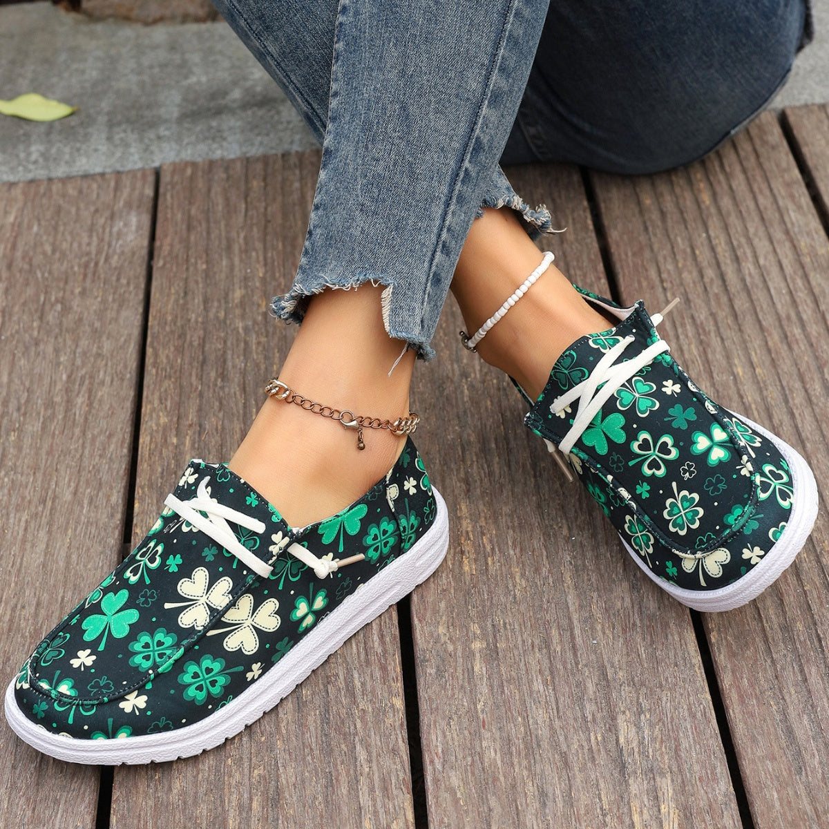 Clover print canvas slip-on sneakers with decorative white laces.