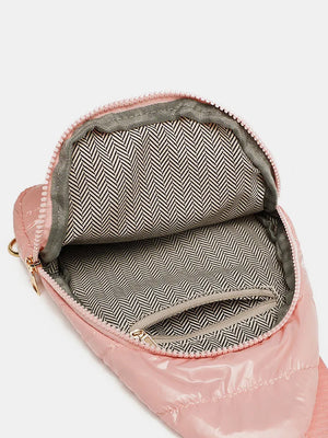 Pink glossy padded sling bag interior with chevron pattern lining and zippered pockets
