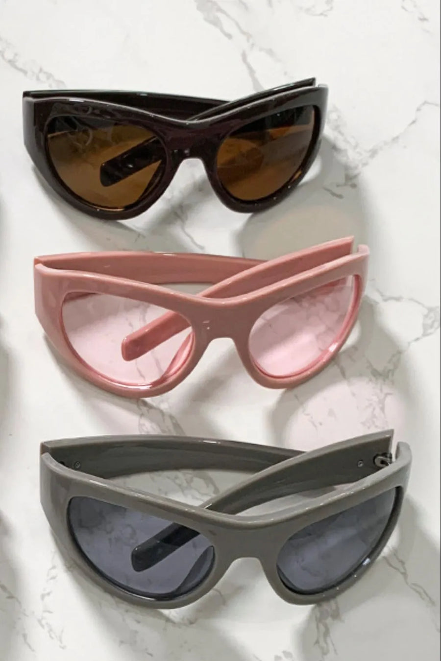 Sporty shield sunglasses in coffee brown, dusty pink, and gray with tinted lenses.