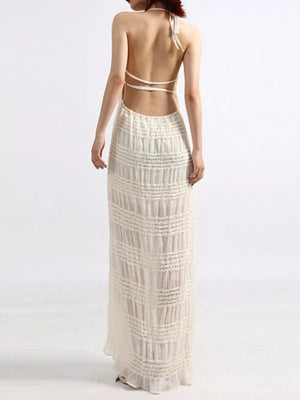 Cream halter maxi dress with open back and textured tiered skirt.