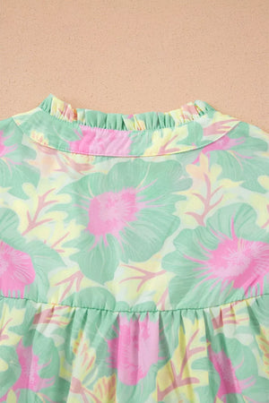 Pastel floral print polyester blouse with ruffled mock neck and tiered hem.