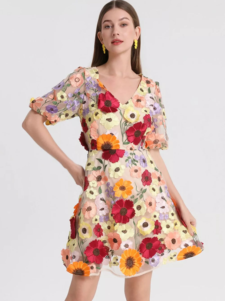 Sheer mesh mini dress with colorful floral embroidery, V-neck, and puff sleeves.