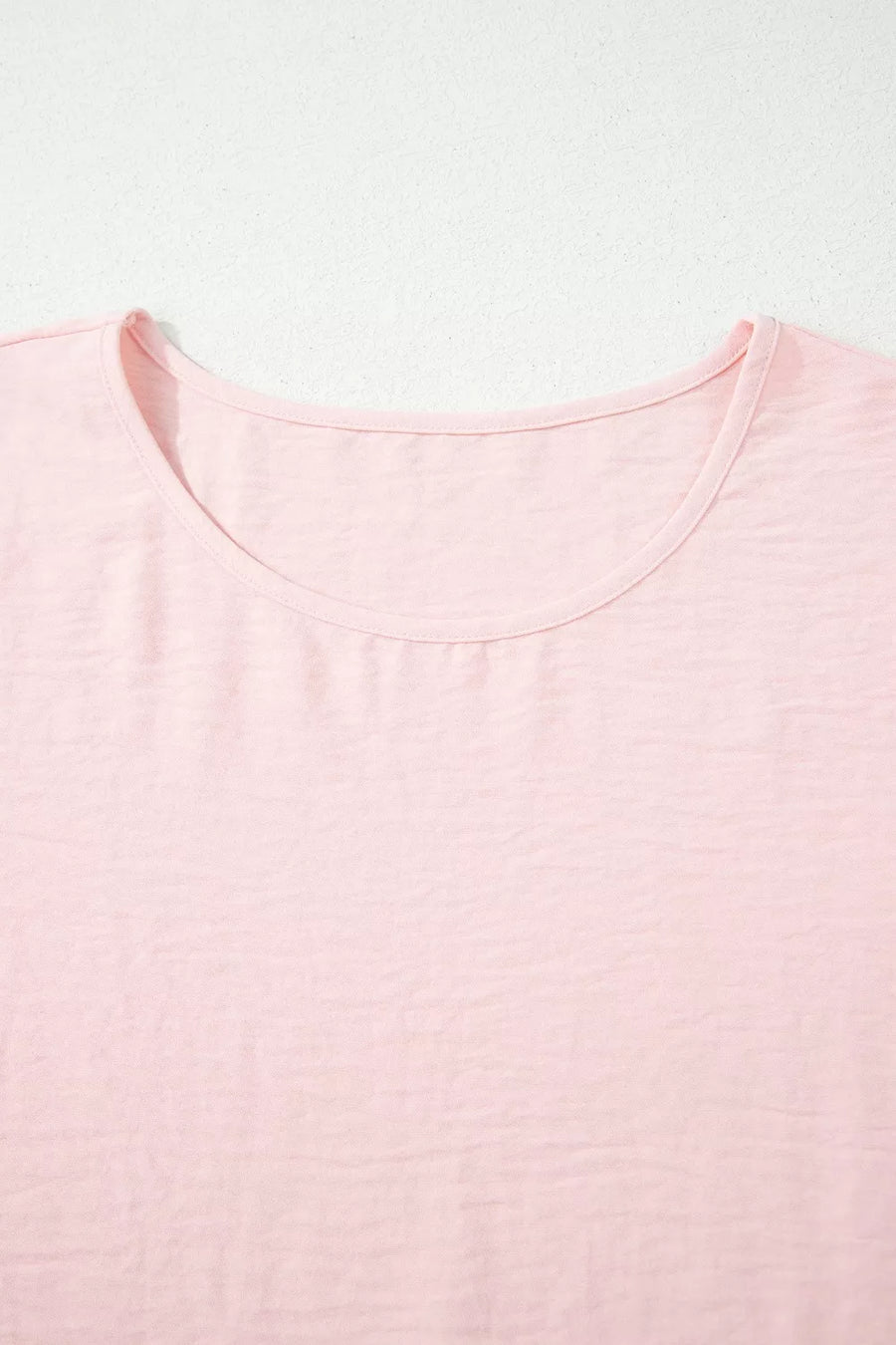 Blush pink polyester blouse with short sleeves and a ruffled neckline.
