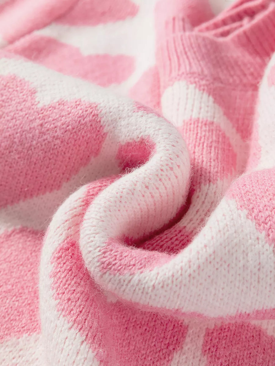 Charming heart pattern knit sweater in blush pink and white acrylic, showing cozy texture.