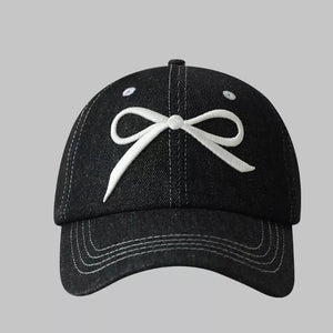 Black baseball cap with white embroidered bow accent