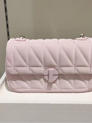 Pink quilted flap chain bag with a turn-lock closure.