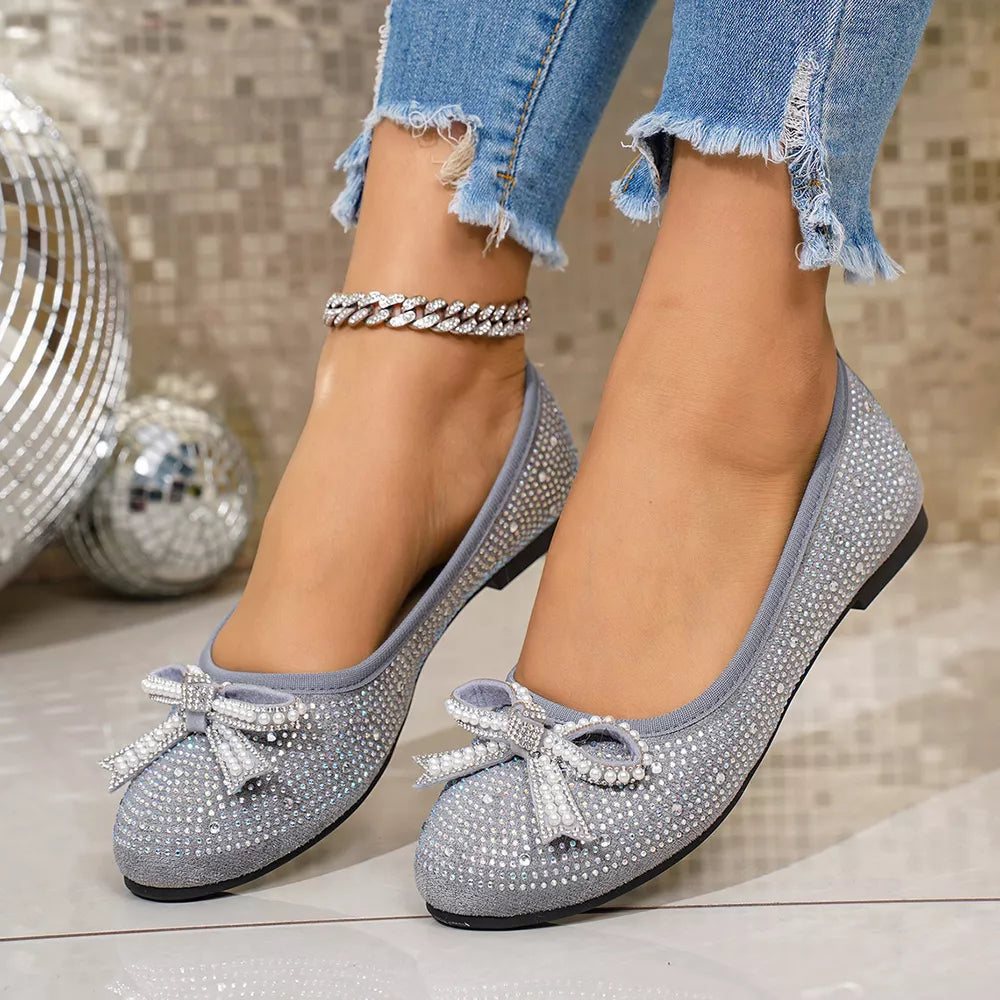 Gray rhinestone-embellished bow flats with a subtle anklet detail.
