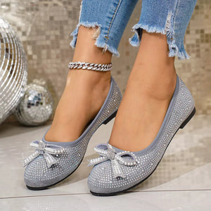 Gray rhinestone-embellished bow flats with a subtle anklet detail.