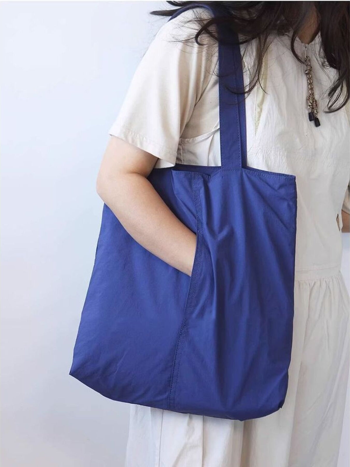 Spacious royal blue nylon shoulder bag with exterior slip pocket.