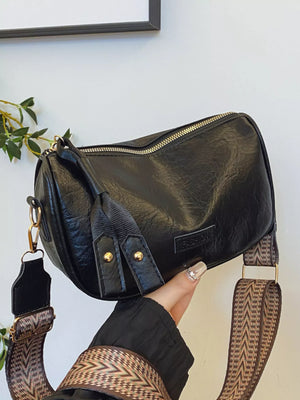 Black crossbody bag with patterned strap and gold hardware.